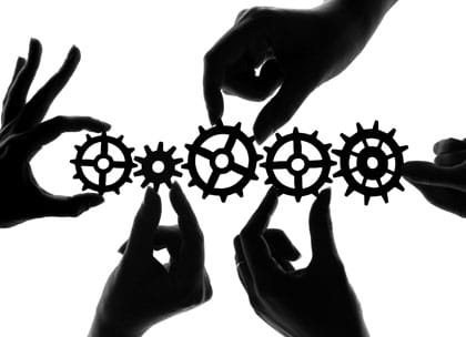 Silhouetted hands holding cogs